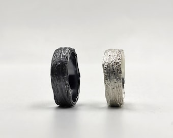 May include: Two textured silver rings, one black and one silver, with a wood-like pattern.
