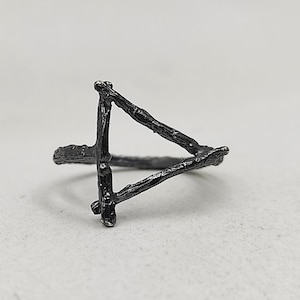 May include: A black triangle ring made of twisted metal, resembling branches.
