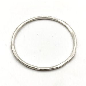 May include: A simple silver bangle bracelet with a hammered finish.