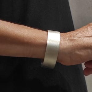May include: A silver cuff bracelet with a brushed finish.