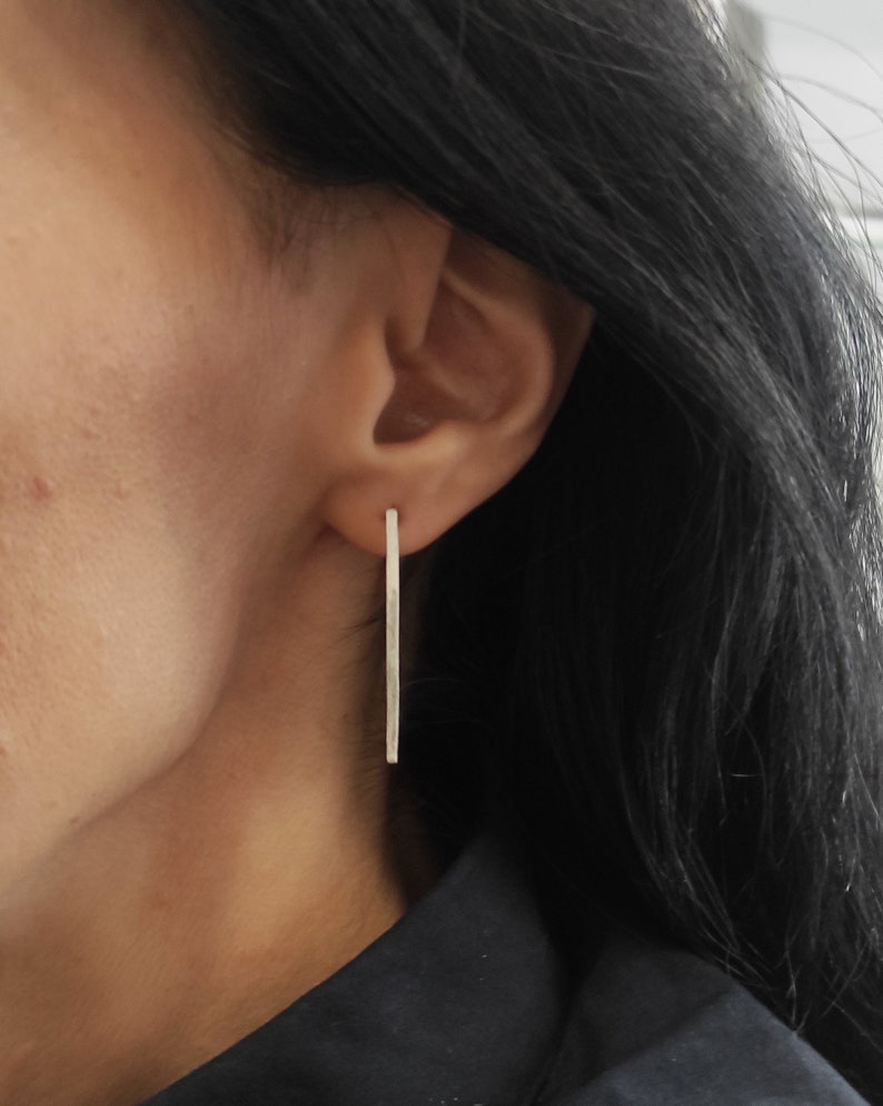 May include: A pair of silver earrings with a long, thin, rectangular shape.