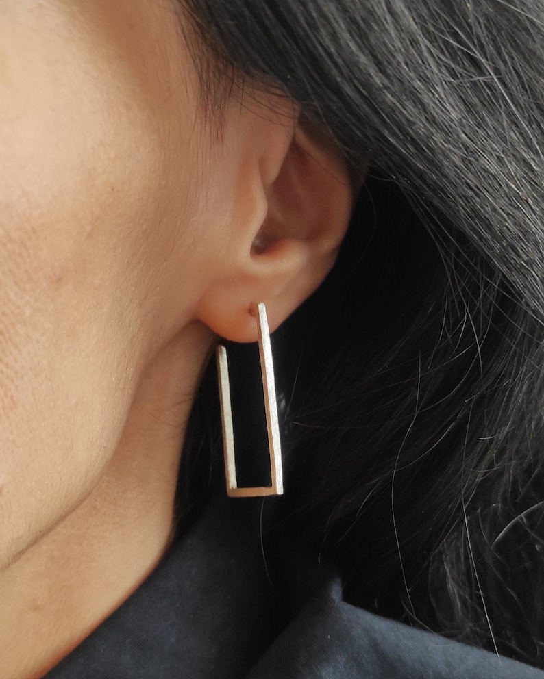 May include: Silver rectangle hoop earrings with a textured finish.