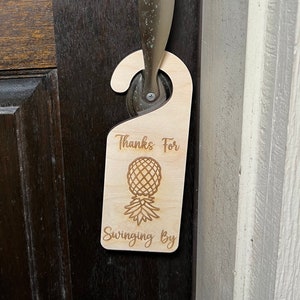 May include: A wooden door hanger with the text "Thanks for swinging by" and a pineapple graphic.
