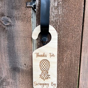 May include: Wooden door hanger with a pineapple design and the text "Thanks for swinging by".