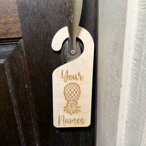 May include: A wooden door hanger with a pineapple design and the text "Your Names".