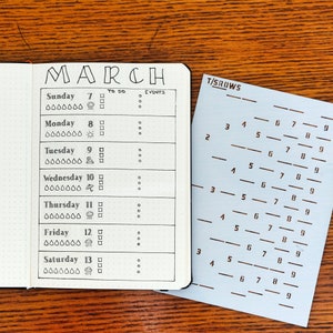 Peut inclure: Un agenda noir et blanc avec le mot "MARCH" en haut. L'agenda a une mise en page quotidienne avec de l'espace pour les listes de t&acirc;ches et les &eacute;v&eacute;nements. L'agenda est ouvert au mois de mars et comporte une grille de nombres de 2 &agrave; 9 sur le c&ocirc;t&eacute; droit de la page.