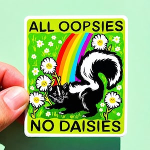 May include: A rectangular sticker featuring a black and white skunk standing in a green field with white daisies, a colourful rainbow, and the black text ALL OOPSIES NO DAISIES printed at the top and bottom of the design on a bright green background.