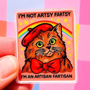 May include: A rectangular sticker featuring a cartoon cat wearing a red beret and bow tie, with a rainbow and stars in the background. The text reads "I'M NOT ARTSY FARTSY I'M AN ARTISAN FARTISAN."