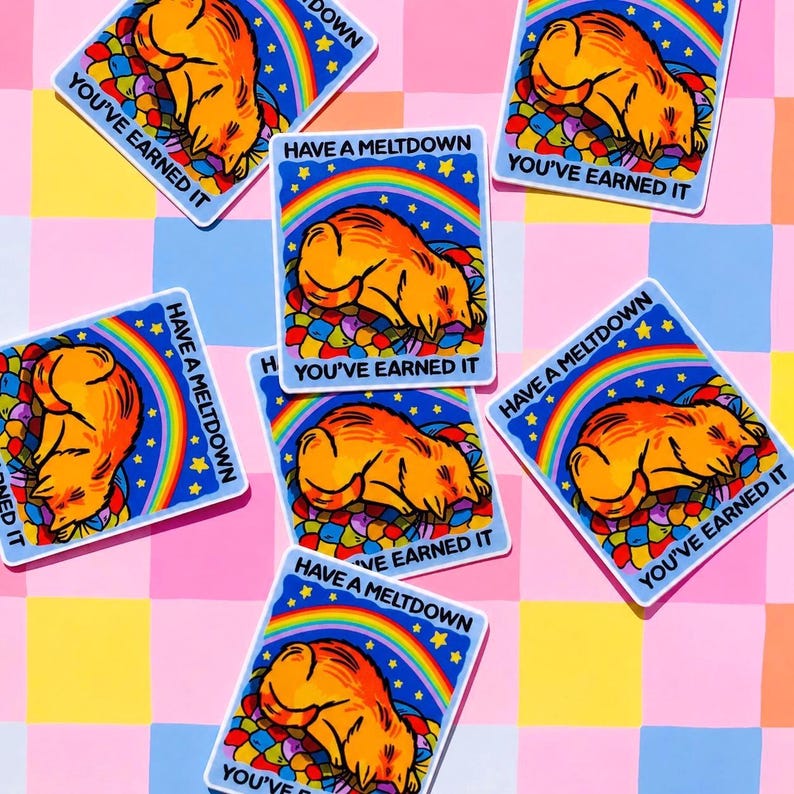 Puede incluir: Pegatinas rectangulares con una ilustraci&oacute;n de dibujos animados de un gato naranja acurrucado, rodeado de formas coloridas. Cada pegatina tiene el texto "HAVE A MELTDOWN" y "YOU'VE EARNED IT" sobre un fondo azul con un arco&iacute;ris y estrellas.