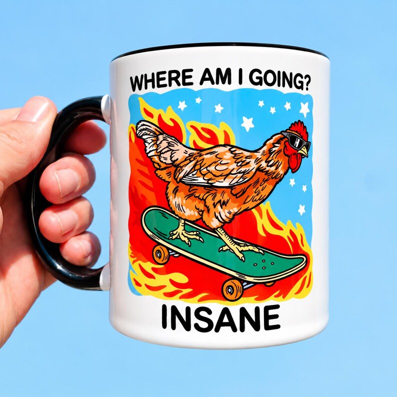 Puede incluir: Una taza de cer&aacute;mica blanca con asa y borde negros, que presenta un gr&aacute;fico de un pollo marr&oacute;n con gafas de sol sobre un monopat&iacute;n verde entre llamas naranjas y estrellas blancas, con el texto WHERE AM I GOING? en la parte superior e INSANE abajo.