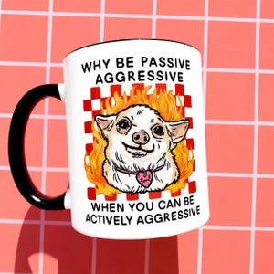 May include: White ceramic mug with a black handle and rim. The mug features a cartoon chihuahua with flames and the text "WHY BE PASSIVE AGGRESSIVE WHEN YOU CAN BE ACTIVELY AGGRESSIVE."