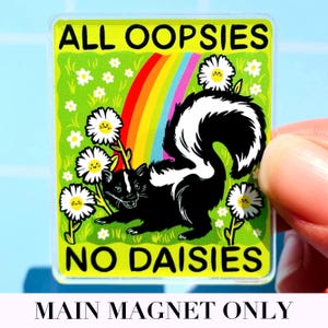 May include: A rectangular magnet featuring a black and white skunk standing in a green field with white daisies and a rainbow. The text ALL OOPSIES is printed in black at the top, and NO DAISIES is printed in black at the bottom of the magnet.