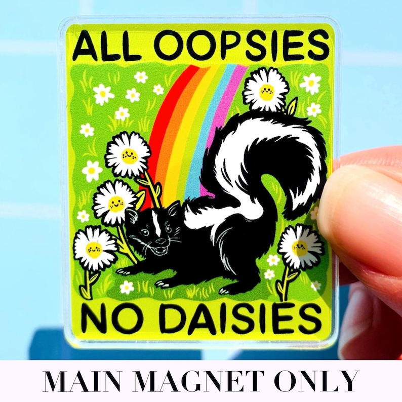 May include: A rectangular magnet featuring a black and white skunk standing in a green field with white daisies and a rainbow. The text ALL OOPSIES is printed in black at the top, and NO DAISIES is printed in black at the bottom of the magnet.
