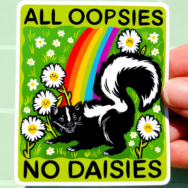 May include: A rectangular sticker featuring a black and white skunk standing in a green field with white daisies and a colourful rainbow. The text ALL OOPSIES is printed at the top and NO DAISIES is printed at the bottom in black capital letters.