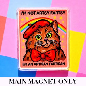 May include: A rectangular magnet featuring a cartoon cat wearing a red beret and bow tie. The cat has green eyes and a rainbow behind it. Text on the magnet reads "I'M NOT ARTSY FARTSY" and "I'M AN ARTISAN FARTISAN".