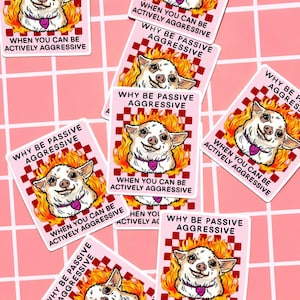 May include: Pink stickers with a cartoon chihuahua in flames. The stickers have the text "WHY BE PASSIVE AGGRESSIVE" and "WHEN YOU CAN BE ACTIVELY AGGRESSIVE". The chihuahua wears a purple heart collar.