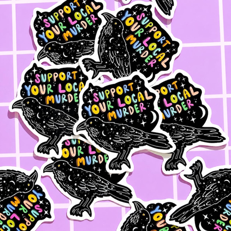 May include: A collection of stickers featuring a black crow illustration with a starry night design. Each sticker has the text "Support Your Local Murder" in colorful lettering. The stickers are on a purple grid background.
