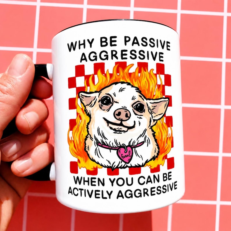 May include: White ceramic mug with a black handle and rim, featuring a cartoon chihuahua in flames. The mug has the text "WHY BE PASSIVE AGGRESSIVE WHEN YOU CAN BE ACTIVELY AGGRESSIVE". The dog wears a pink heart-shaped collar.