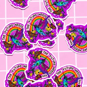 May include: Multiple die-cut stickers featuring a vibrant, tie-dye colored hummingbird in flight, a monarch butterfly, yellow flowers, and a rainbow arch. The text "THE FUTURE NEEDS YOU" is printed in a circular arc around the central design.