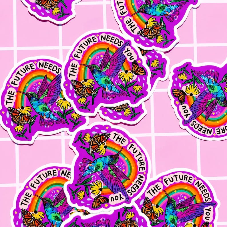 May include: Multiple die-cut stickers featuring a vibrant, tie-dye colored hummingbird in flight, a monarch butterfly, yellow flowers, and a rainbow arch. The text "THE FUTURE NEEDS YOU" is printed in a circular arc around the central design.