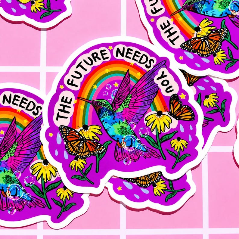 May include: A die-cut sticker featuring a vibrant hummingbird in flight, surrounded by monarch butterflies, yellow flowers, and a rainbow. The text THE FUTURE NEEDS YOU is printed in black along the top edge against a bright purple background.