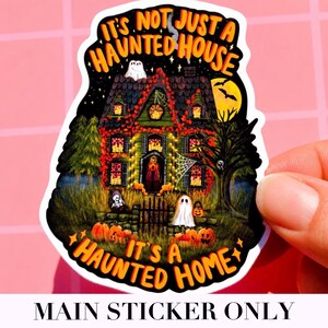 May include: A colorful Halloween sticker featuring a haunted house with pumpkins, ghosts, and a full moon. The sticker has the text "It's Not Just A Haunted House, It's A Haunted Home" in orange and black.