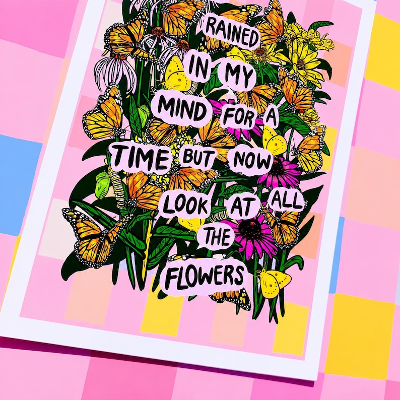 May include: A framed art print featuring a vibrant floral arrangement with monarch butterflies. The artwork includes text that reads "Rained in my mind for a time but now look at all the flowers." The print has a pink and white border.