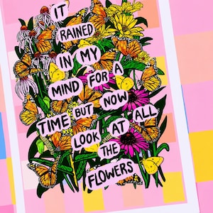 May include: A colorful art print featuring a vibrant arrangement of butterflies and flowers. The artwork includes text that reads "It rained in my mind for a time but now look at the flowers." The background is pink with geometric shapes.