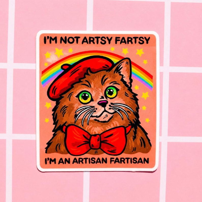 Pu&ograve; includere: Un adesivo quadrato raffigurante un gatto marrone che indossa un basco rosso e un papillon rosso. Sopra il gatto ci sono un arcobaleno e stelle gialle su sfondo color pesca. Il testo recita I'M NOT ARTSY FARTSY e I'M AN ARTISAN FARTISAN.