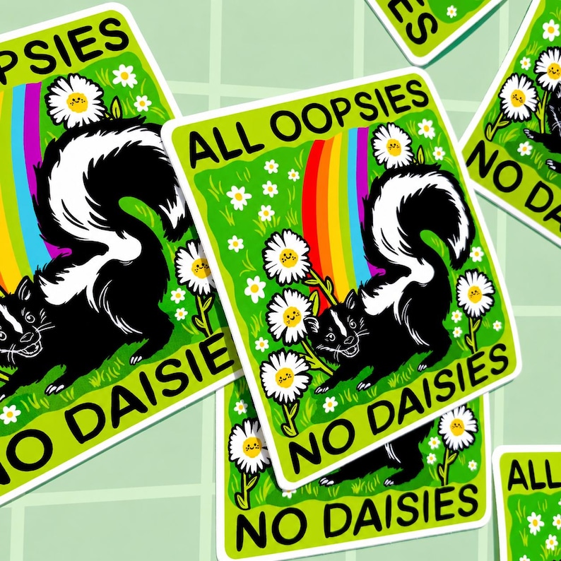 May include: A rectangular sticker featuring a black and white skunk on a bright green background with white daisies, a colourful rainbow, and the black text ALL OOPSIES NO DAISIES. The design includes several daisy flowers with small smiling faces.