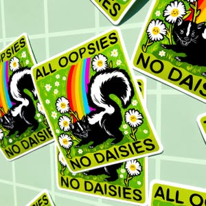 May include: A rectangular sticker featuring a black and white skunk standing in a green field with white daisies and a colourful rainbow. The text ALL OOPSIES is printed at the top and NO DAISIES is printed at the bottom in bold black letters.