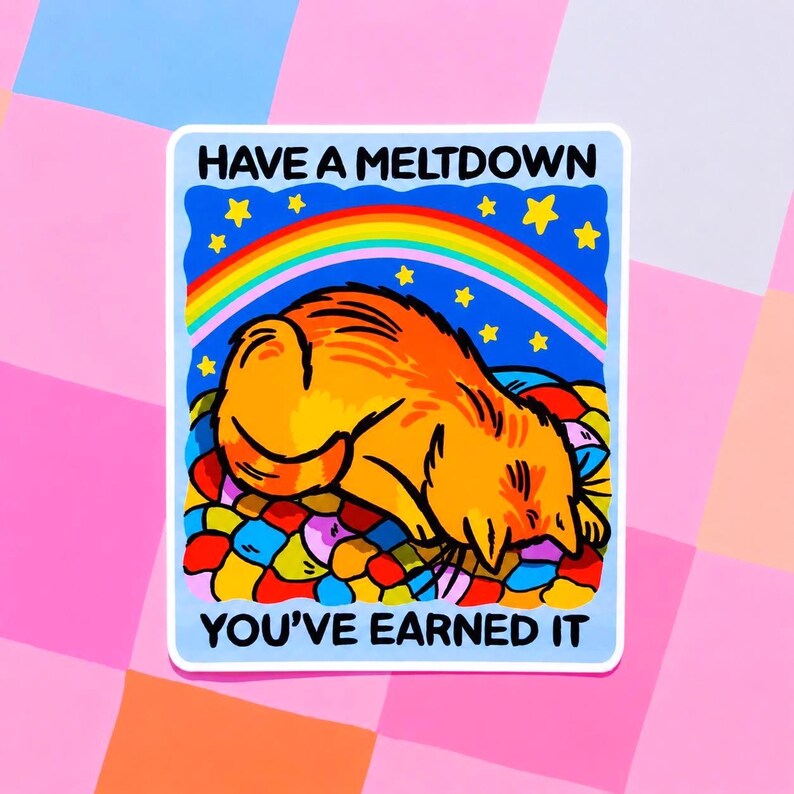 Puede incluir: Una pegatina con una ilustraci&oacute;n de dibujos animados de un gato naranja acostado sobre una cama colorida. La pegatina tiene un borde azul y el texto "HAVE A MELTDOWN YOU'VE EARNED IT" con un arco&iacute;ris y estrellas.
