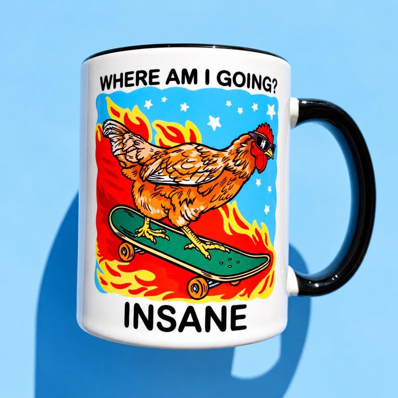 Puede incluir: Una taza de cer&aacute;mica blanca con asa y borde negros que presenta un gr&aacute;fico de un pollo naranja con gafas de sol sobre un monopat&iacute;n verde entre llamas naranjas y estrellas blancas. El texto dice WHERE AM I GOING? y INSANE.