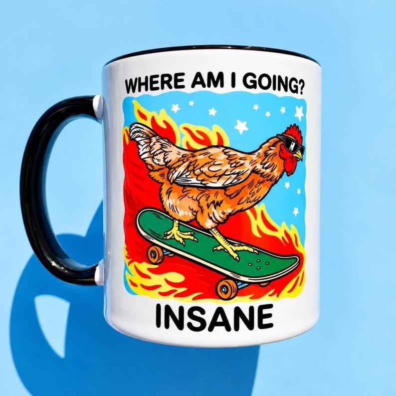 Puede incluir: Una taza de cer&aacute;mica blanca con asa negra que presenta un gr&aacute;fico de una gallina marr&oacute;n con gafas de sol sobre un monopat&iacute;n verde. El fondo muestra llamas naranjas y un cielo azul con estrellas blancas. El texto dice WHERE AM I GOING? e INSANE.