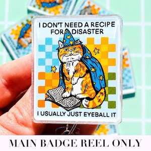 May include: A rectangular acrylic badge reel featuring an orange tabby cat wearing a blue wizard hat and cape with yellow stars. The cat sits by an open book. The text reads: I DON'T NEED A RECIPE FOR DISASTER I USUALLY JUST EYEBALL IT.