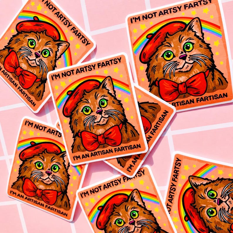 Pu&ograve; includere: Un adesivo quadrato raffigurante un gatto marrone che indossa un basco rosso e un papillon rosso. Un arcobaleno si inarca dietro il gatto su uno sfondo color pesca con stelle gialle. Il testo recita I'M NOT ARTSY FARTSY I'M AN ARTISAN FARTISAN.
