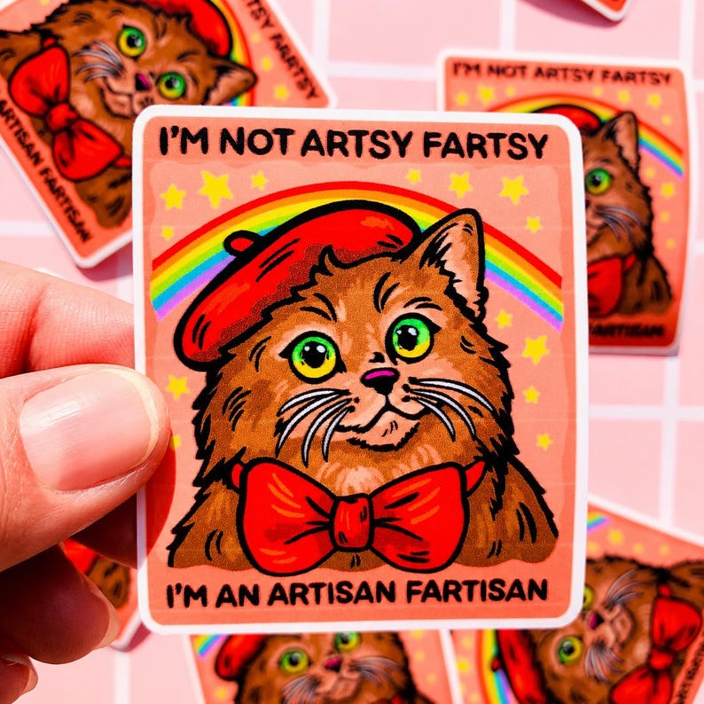 Pu&ograve; includere: Un adesivo quadrato raffigurante un gatto marrone che indossa un basco rosso e un papillon rosso. Sopra il gatto, il testo recita I'M NOT ARTSY FARTSY, e sotto, I'M AN ARTISAN FARTISAN. Un arcobaleno e stelle gialle su uno sfondo color pesca.