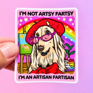 May include: A square sticker featuring a long-haired dog wearing a red beret with a paintbrush and pink glasses. The background shows a rainbow, a canvas on an easel, and a stack of books. Text reads: I'M NOT ARTSY FARTSY I'M AN ARTISAN FARTISAN.