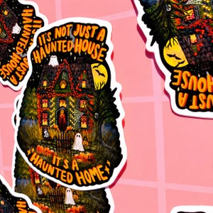 May include: A sticker with a detailed illustration of a haunted house, pumpkins, ghosts, and the text "It's Not Just A Haunted House, It's A Haunted Home." The house is lit up with orange lights, and a full moon is in the background. A spooky Halloween theme.