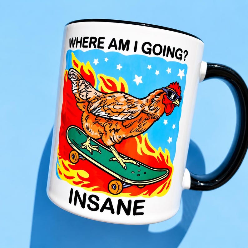 Puede incluir: Una taza de cer&aacute;mica blanca con asa y borde negros que presenta un gr&aacute;fico de un pollo marr&oacute;n con gafas de sol sobre un monopat&iacute;n verde. El fondo muestra llamas naranjas y estrellas blancas sobre un cielo azul. Texto: WHERE AM I GOING? e INSANE.