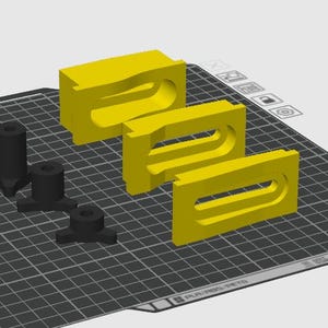 May include: Three yellow rectangular blocks with elongated horizontal cutouts and three black cylindrical components with three-pronged bases arranged on a digital grid interface, representing a 3D model design for manufacturing components.
