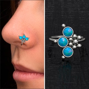 Può includere: Un anello per il naso in argento con un gruppo di cinque pietre di opale blu turchese. L'anello è mostrato sul naso di una modella.