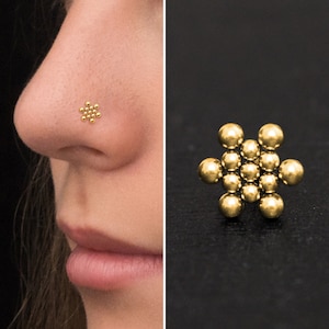 May include: Gold nose ring featuring a delicate flower design crafted from tiny beads.