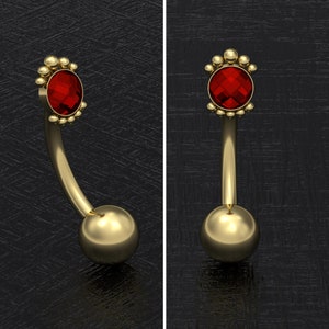 Puede incluir: Anillo de ombligo dorado con una gema roja y un grupo de pequeñas cuentas doradas en cada extremo.