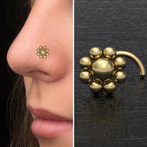 Könnte beinhalten: Goldener Nasenring mit einem Blumendesign aus kleinen runden Perlen.