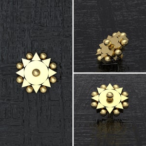 May include: A gold-colored, star-shaped object with a central circle and smaller circles around the perimeter. The object is on a black background.