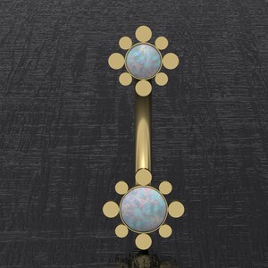 May include: Gold body jewelry with two opal gemstones set in a circular design with smaller gold circles surrounding each stone.
