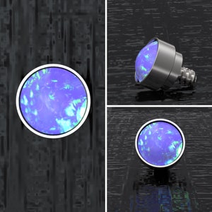May include: A close-up of a blue opal gemstone set in a silver-toned metal bezel. The gemstone has a swirling pattern of blue, green, and white.