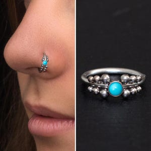 May include: A silver nose ring with a turquoise gemstone. The ring is decorated with small silver beads.