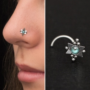 May include: Silver nose ring with a turquoise gemstone in the centre of a star-shaped design.